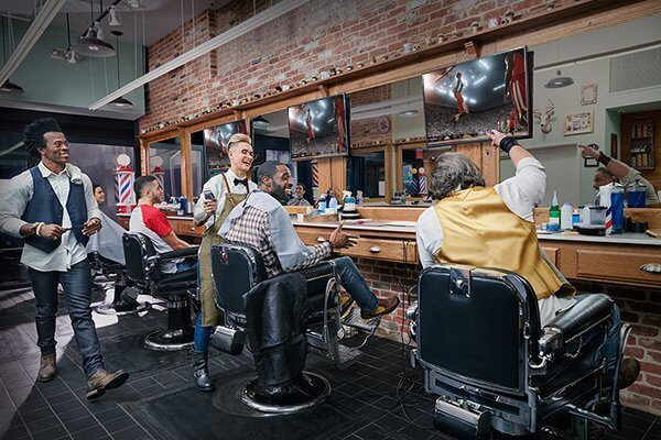 men at barber shop talking and watching tv