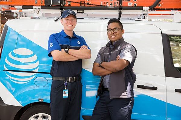 two at&t technicians standing in front of service van with arms crossed and smiling
